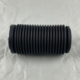 Upper-middle macro crop of front suspension strut dust cover on light grey wrinkled kraft paper